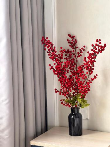 a black vase with red flowers on a table at Hoa Homestay Hạ Long 2909 in Ha Long