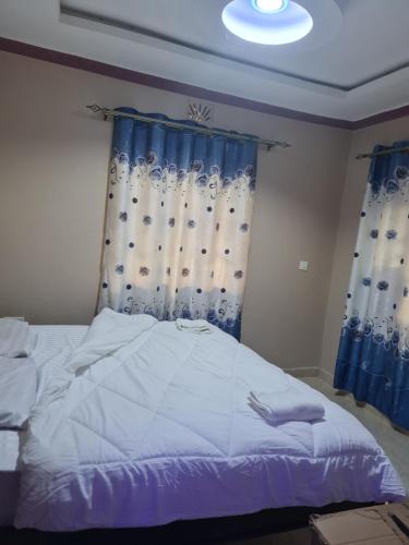 1 dormitorio con 1 cama grande y cortinas azules en Christa's haven, en Siaya