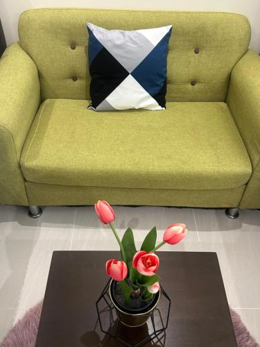uma sala de estar com um sofá e uma mesa com flores em Cozy*Home @ Riverine Diamond Kuching em Kuching