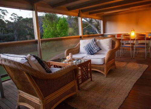 a screened in porch with two chairs and a table at Chalet La Piste in Merrijig