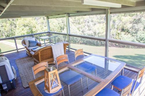 a screened in porch with a glass table and chairs at Chalet La Piste in Merrijig