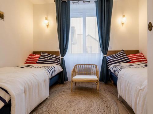 a room with two beds with a chair and a window at Villa face à la mer avec terrasse privative, confort moderne, Wi-Fi gratuit à Saint-Nazaire - FR-1-306-1260 in Saint-Nazaire