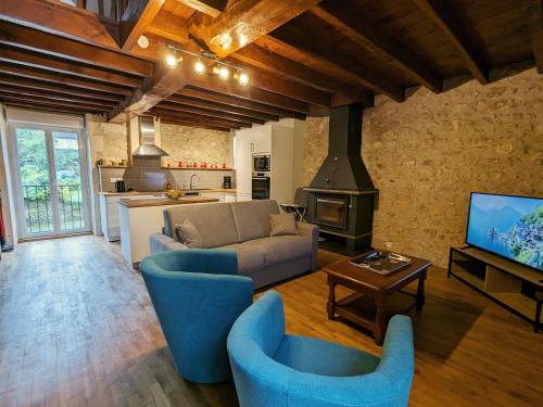 Il comprend un salon doté de fauteuils bleus, d'un canapé et d'une télévision. dans l'établissement Ancien Moulin Authentique, Terrasse Privée et Rivière en Berry, Parc Naturel de la Brenne - FR-1-591-560, à Saint-Aigny