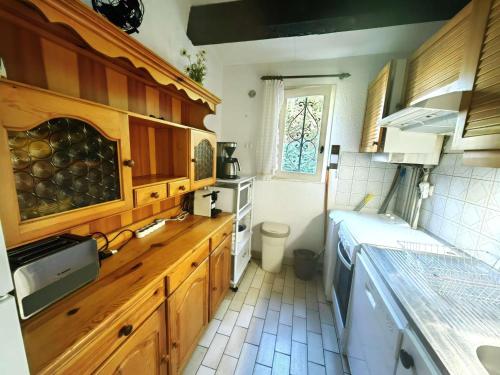 une cuisine avec des armoires en bois et un évier dans l'établissement Villa Mitoyenne T4 avec Piscine, Terrasse, Parking et Proche Plage - Animaux Bienvenus - FR-1-607-179, au Cap d'Agde