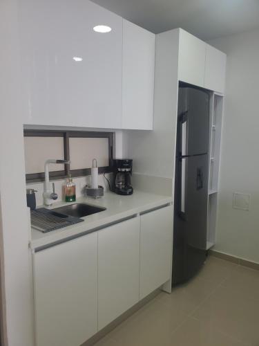 a kitchen with white cabinets and a stainless steel refrigerator at Samaria club de playa Santa marta in Gaira