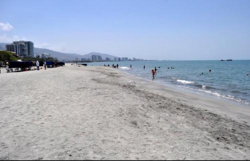 a beach with people in the water and a group of people at Samaria club de playa Santa marta in Gaira