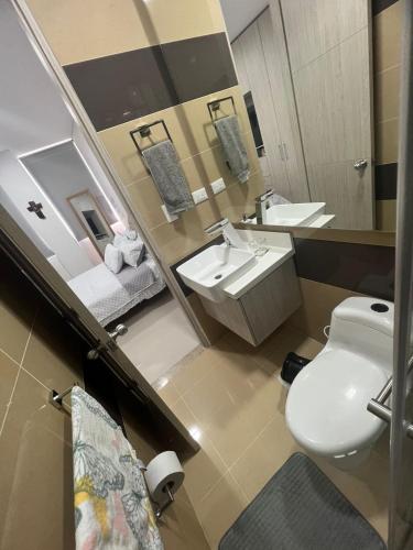 a bathroom with a toilet and two sinks and a mirror at Samaria club de playa Santa marta in Gaira