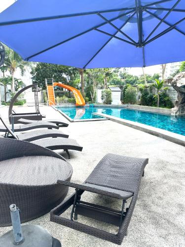 a group of chairs and an umbrella next to a swimming pool at Club Royal Apartments in North Pattaya