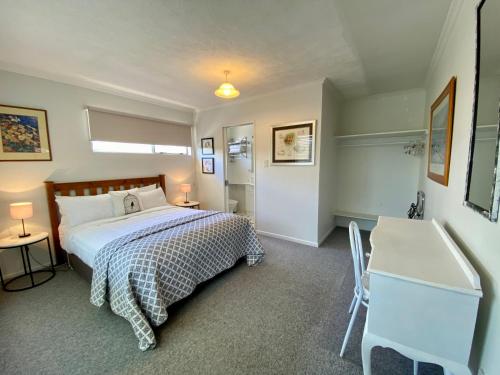 a bedroom with a bed and a desk and a sink at Rathlin Cottage in Twizel