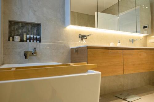 uma casa de banho com um lavatório, uma banheira e um espelho. em Resort Style home close to the Beach with Pool, Sauna and Pizza Oven em Sidney