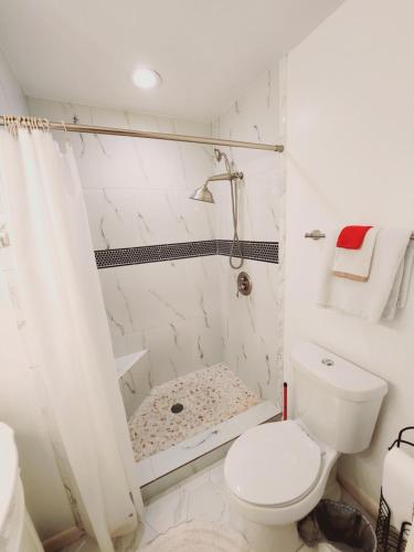 a white bathroom with a shower and a toilet at F3 close to front heated pool in Mallory Park
