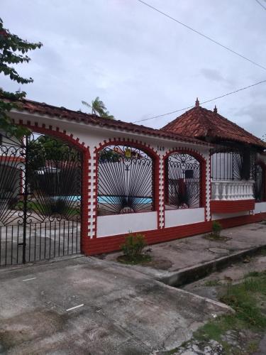 un cenador rojo y blanco con una valla negra en Casarão Farol da Marise Sol en Belém