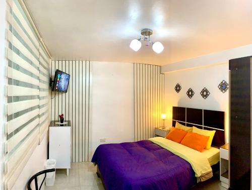 a bedroom with a purple bed and a tv at Cusco Magico 9 - Loft Santa Ursula in Cusco