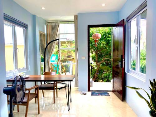 a dining room with a table and chairs and a door at Azalea Apartment in Hanoi