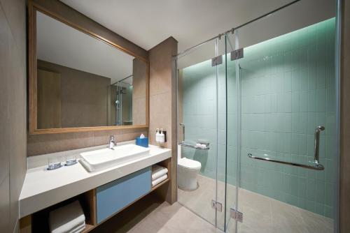 een badkamer met een wastafel en een glazen douche bij IXORA Ho Tram By Fusion in Ho Tram