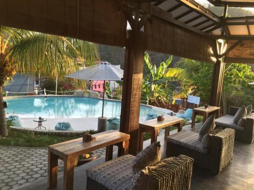 a pool with couches and tables and an umbrella at Wae Molas Hotel in Labuan Bajo