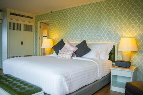 a bedroom with a large white bed with pillows at Grand China Bangkok in Bangkok
