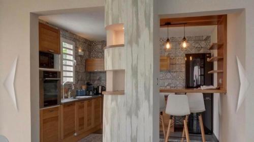 - une cuisine avec des placards en bois et des tabourets blancs dans l'établissement L'Olivine, à Saint-Pierre