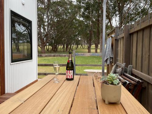 a bottle of wine on a wooden table with a glass at Marlo Hideaway in Marlo