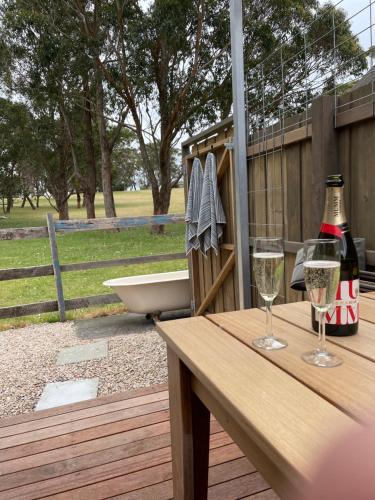 a table with wine glasses and a bath tub on a deck at Marlo Hideaway in Marlo