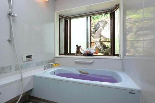 a bath tub with a dog sitting in a window at Nakanoya in Nanto