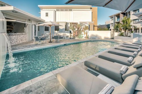 a swimming pool with chaise lounge chairs in front of a house at Essence Peregian Beach Resort - Marram 3 Bedroom Luxury Home in Peregian Beach