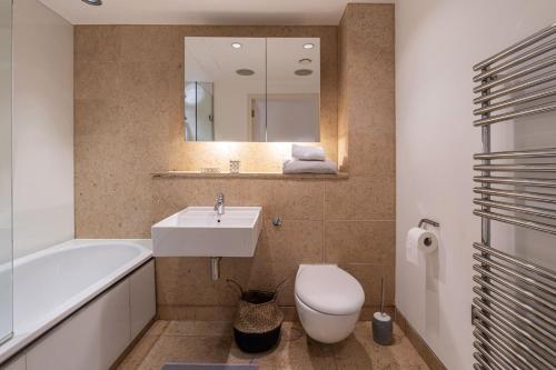een badkamer met een wastafel, een toilet en een spiegel bij London Mayfair W1 in Londen