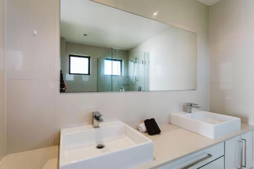 uma casa de banho com 2 lavatórios e um espelho grande em ABC On Wanaka Bay Support Local em New Plymouth