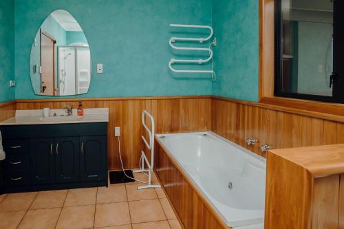 a bathroom with a tub and a sink and a mirror at Mt Taranaki Vista 