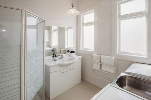 a white bathroom with a sink and a shower at The Front Office in New Plymouth