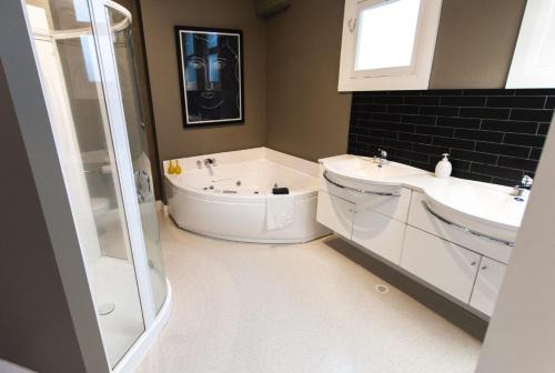 een badkamer met een bad, 2 wastafels en een douche bij Stay Central The Penthouse in New Plymouth