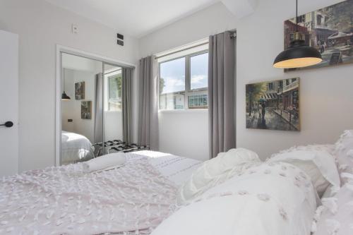 a white bedroom with a bed and a window at Chic IN THE City in New Plymouth