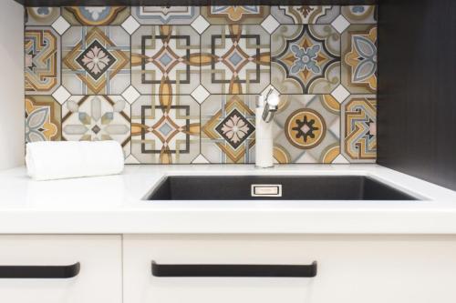 a sink in a kitchen with a tile wall at Chic IN THE City in New Plymouth