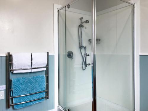 La salle de bains est pourvue d'une douche avec une porte en verre. dans l'établissement The Brooklands Bungalow, à New Plymouth