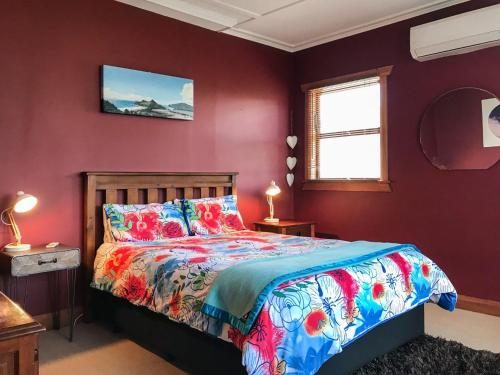 a bedroom with purple walls and a bed with a colorful bedspread at The Brooklands Bungalow in New Plymouth