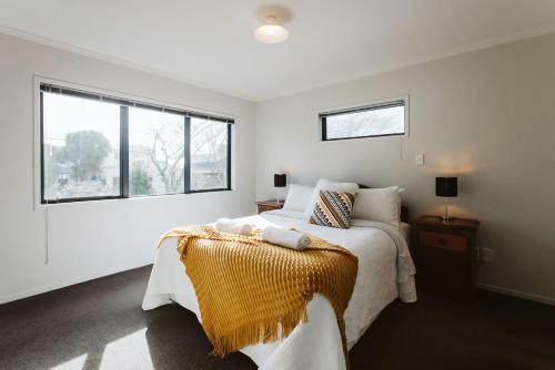 a white bedroom with a bed and a window at Seven By The Sea Tourist Hot Spot in New Plymouth