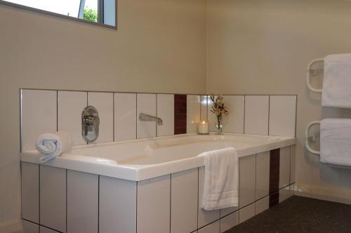 a bathroom with a large white tub with towels at Relax On Richmond Modern Large Beach House in New Plymouth