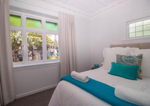 a bedroom with a bed and two windows at Fox Lodge Central Location in New Plymouth