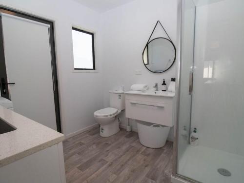 a white bathroom with a toilet and a mirror at Aqua Vista On Arden - Support Local in Oakura