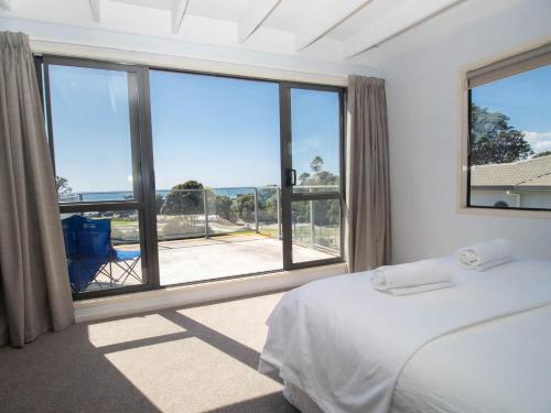 um quarto com uma cama e uma grande janela em Aqua Vista On Arden - Support Local em Oakura