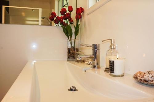 a bathroom sink with a vase of red tulips and a candle at Memories On Mcfarlane Prime Oakura Location in Oakura