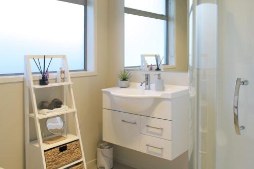 a bathroom with a sink and a mirror and a shower at Escape To Buller Prime Holiday Location in New Plymouth