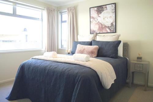 a bedroom with a blue bed with pillows and a window at Escape To Buller Prime Holiday Location in New Plymouth