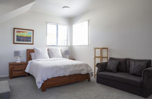 um quarto com uma cama e um sofá em Sunny Ark Apartment em New Plymouth