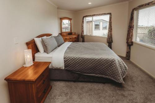 a bedroom with a large bed and a wooden table at Stay At Saddle Row in New Plymouth