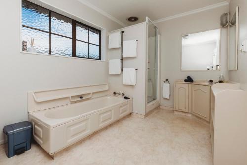 Baño blanco con bañera y lavamanos en Family Fun Swimming Pool Spa Pool, en New Plymouth