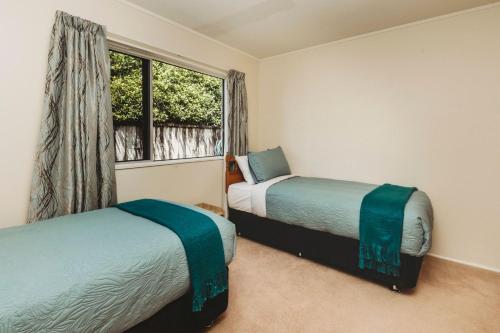 a bedroom with two beds and a window at The Gilbert Getaway in New Plymouth