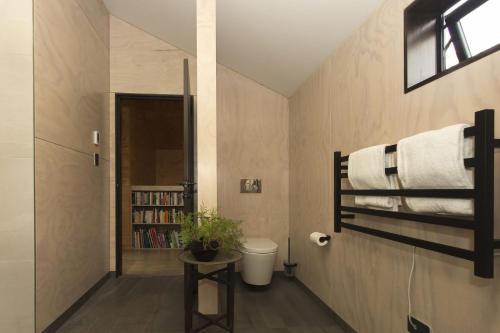uma casa de banho com um WC e uma estante de livros em The Natural Home Prime Fitzroy Location em New Plymouth