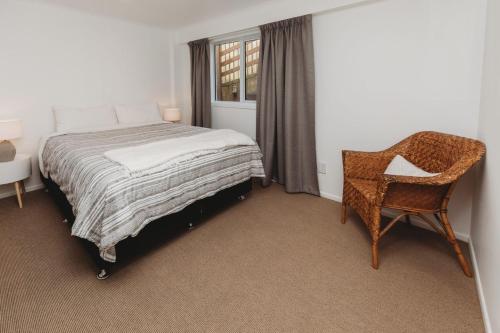 a bedroom with a bed and a chair and a window at Wow On Wanaka Bay in New Plymouth