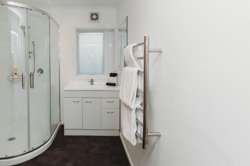 a white bathroom with a shower and a sink at Wow On Wanaka Bay in New Plymouth